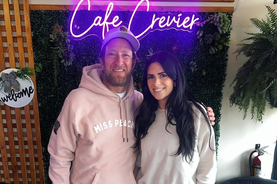 This photo shows a smiling Dave Portnoy with his arm around a smiling Brittany Crevier in front of the Café Crevier sign.