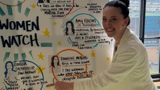 This photo shows Giorgia Caporuscio in front of a sign touting 10 Women to Watch in the hospitality industry at the NYSRA Women in Hospitality conference.