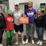 This photo shows Jet's Pizza team members, including on person dressed as the Jet's mascot, presenting a boxed pizza to representatives of RARE (Recreation Authority Roseville & Eastpointe)