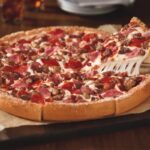 This photo shows a meat lovers pizza with a thick crust.