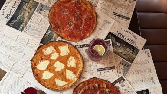 This photo shows the three mobster-themed pizzas arranged over mock newspapers with headlines about Next Door Bar.