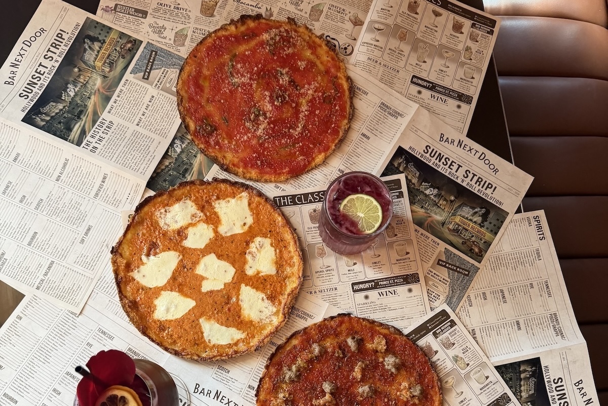 This photo shows the three mobster-themed pizzas arranged over mock newspapers with headlines about Next Door Bar.