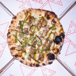 This photo shows a pizza called The Lot on top of Timber Pizza-branded paper.