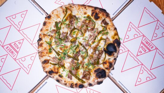 This photo shows a pizza called The Lot on top of Timber Pizza-branded paper.