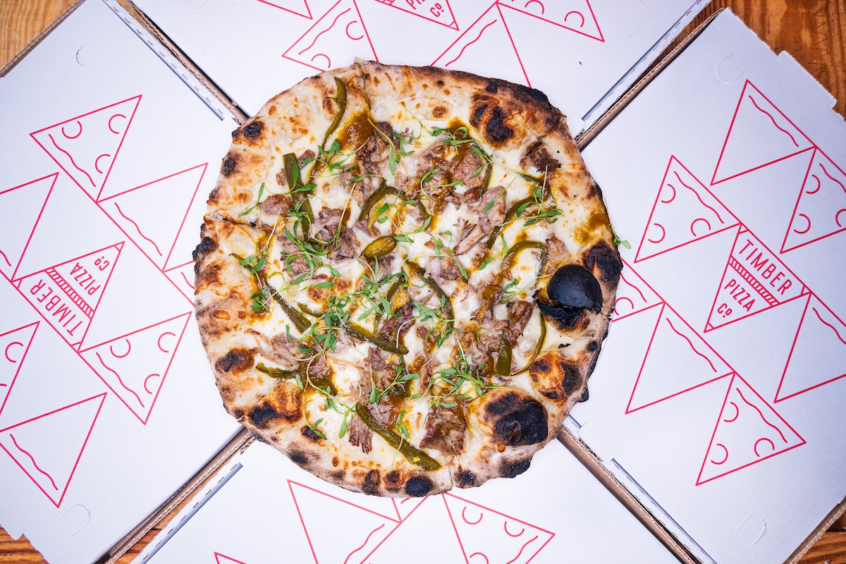 This photo shows a pizza called The Lot on top of Timber Pizza-branded paper.