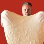 This photo shows Tony Gemignani stretching a gigantic piece of dough into the shape of a heart.