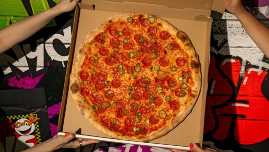 This photo shows two pairs of hands holding a box containing the Shredders Revenge pizza described in the story.