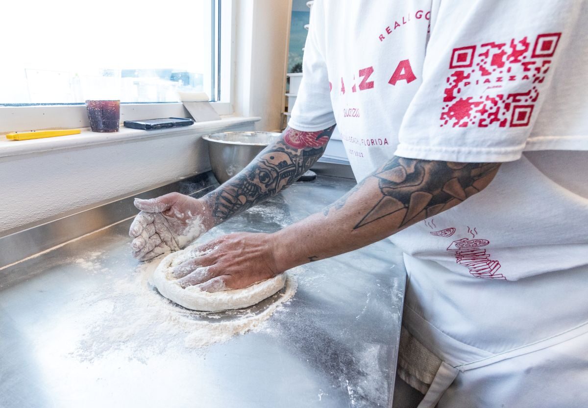 A pizza maker presses dough at Piazza Pizza & Beach Bodega in Pensacola, Florida