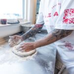 A pizza maker presses dough at Piazza Pizza & Beach Bodega in Pensacola, Florida