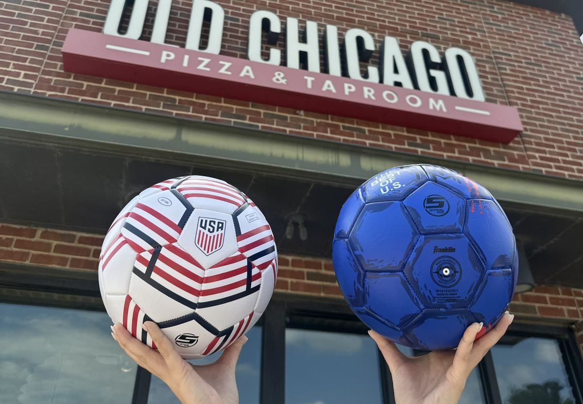 Customers hold soccer balls in front of Old Chicago Pizza + Taproom
