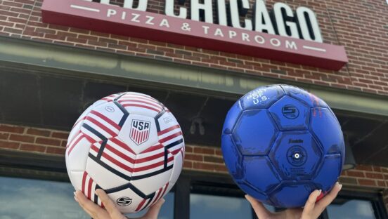 Customers hold soccer balls in front of Old Chicago Pizza + Taproom