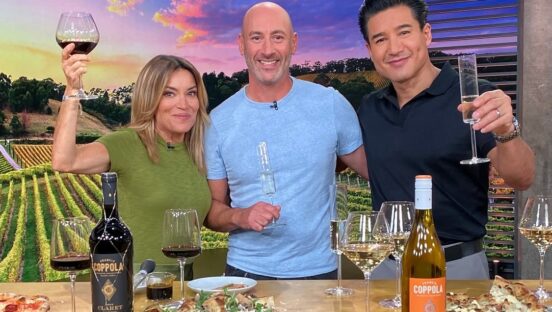 This photo shows Dan Richer in a blue shirt standing between Kit Hoover and Mario Lopez on the set of "Access Hollywood."