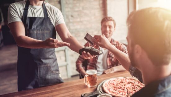 This photo shows a man paying for a pizza with a credit card.
