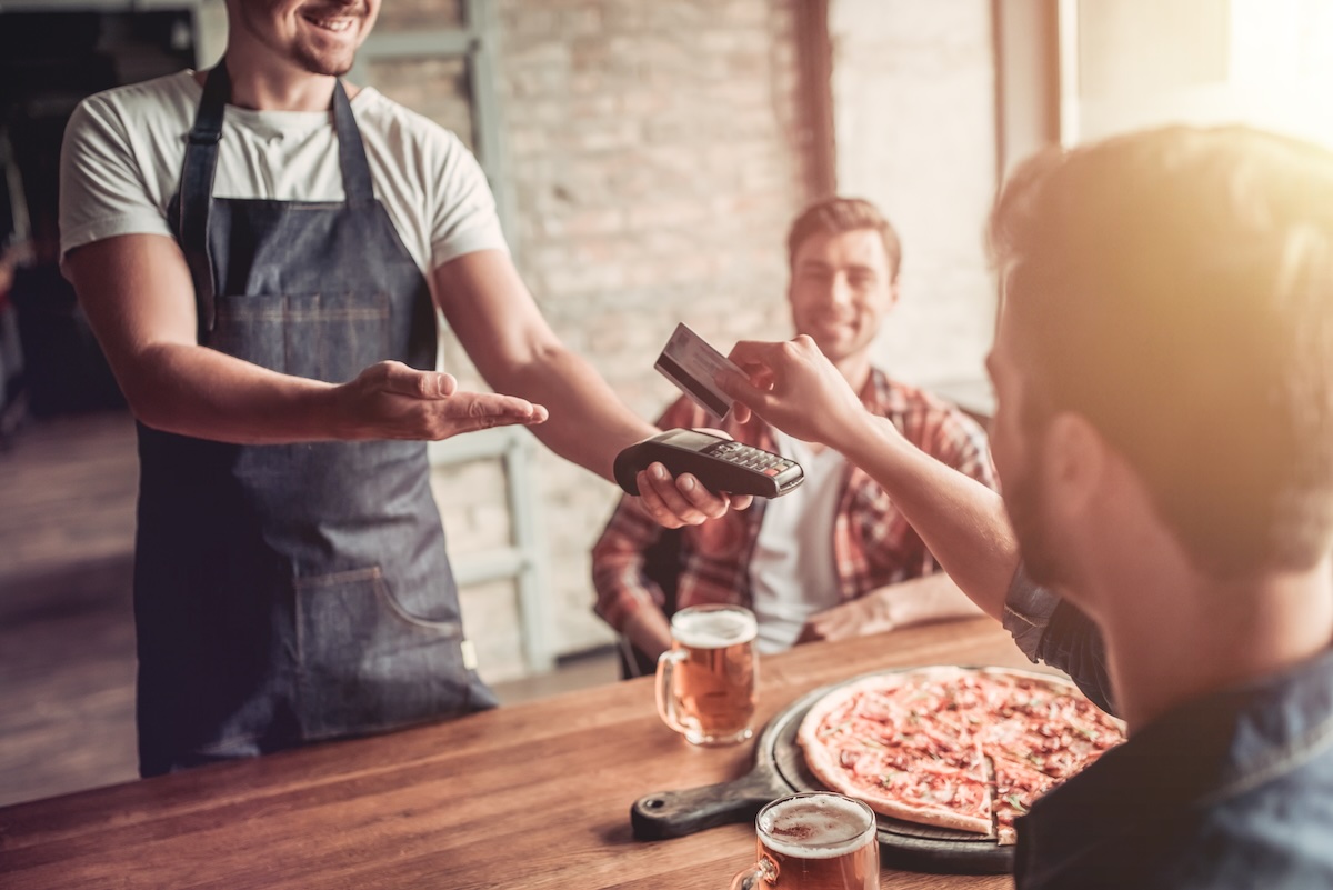 This photo shows a man paying for a pizza with a credit card.