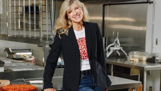 This photo shows Jane Grote Abell smiling and posing in the kitchen of a Donatos Pizza location.