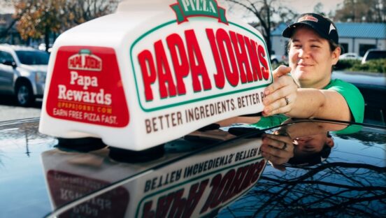 This photo shows a female driver for Papa Johns putting the car toppers sign on her car.