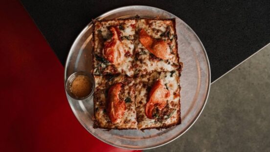 This photo shows the Garbo's Queen Lobster Pizza on a tray against a dark background.