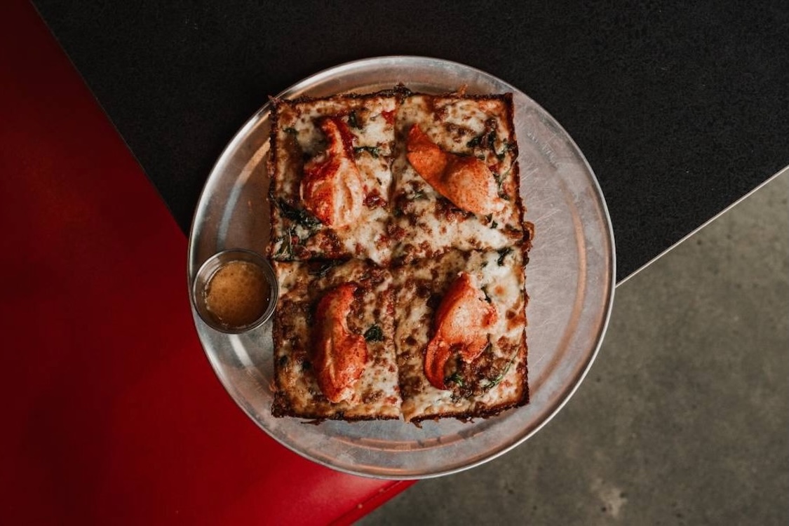 This photo shows the Garbo's Queen Lobster Pizza on a tray against a dark background.
