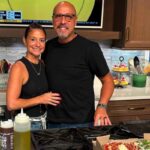 This photo shows Sean Jefairjian and his wife Jessica smiling and standing closely together in their home kitchen.