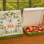 This photo shows a themed customized "Practical Magic 2" pizza box and the Mystic Margherita Pizza in a separate box.