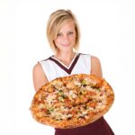 This photo shows a young woman in a cheerleader outfit holding a large pizza with various toppings.