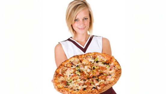 This photo shows a young woman in a cheerleader outfit holding a large pizza with various toppings.