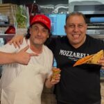This photo shows Daniel Romano giving the thumbs-up while a friend puts his arm around him and enjoys a slice of pizza.