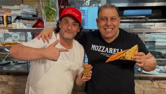 This photo shows Daniel Romano giving the thumbs-up while a friend puts his arm around him and enjoys a slice of pizza.