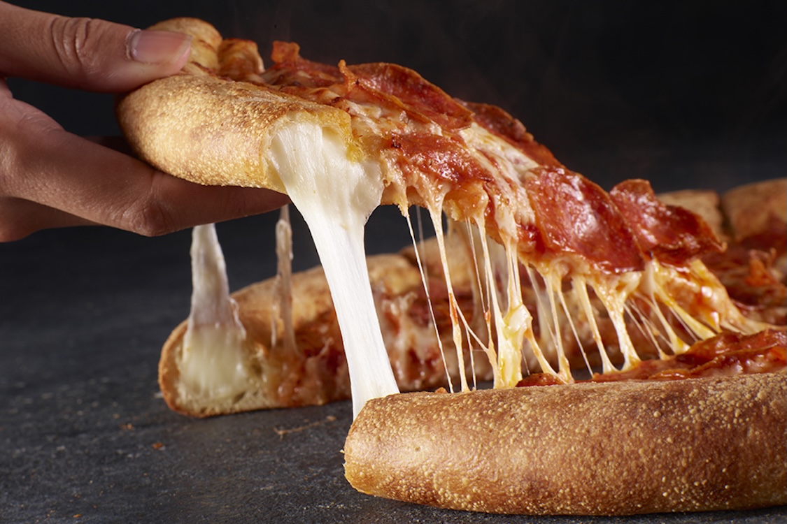 This photo shows someone's hand removing a slice of pizza, with cheese oozing out of the crust, of Papa Johns' Epic Stuffed Crust Pizza.