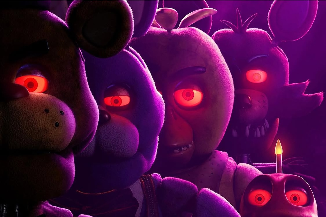 This photo shows a group of creepy animatronic bear characters with glowing red eyes in moody purple lighting.