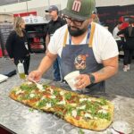 This photo shows Juan Robles making a pizza at a competition.