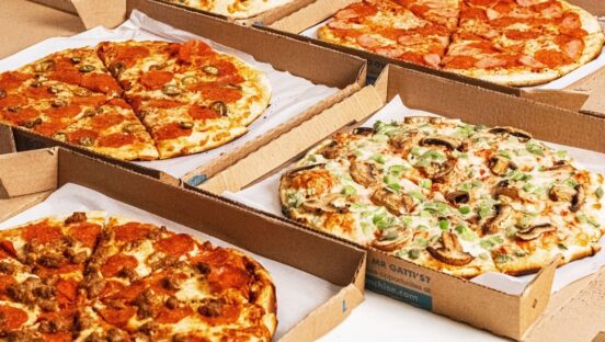 This photo shows an array of different types of pizza in carryout boxes.