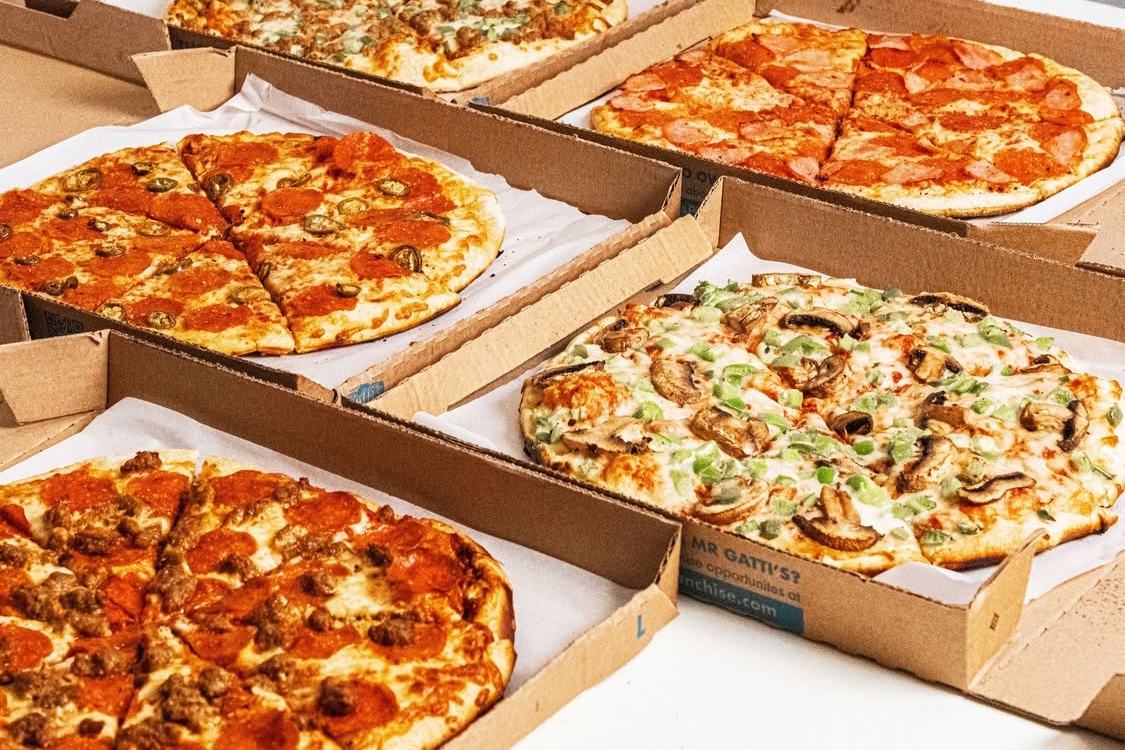 This photo shows an array of different types of pizza in carryout boxes.