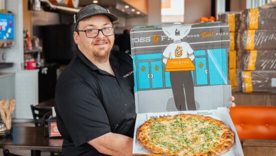 This photo shows Nick Sanford holding up a pizza in the Pizza Bib box.