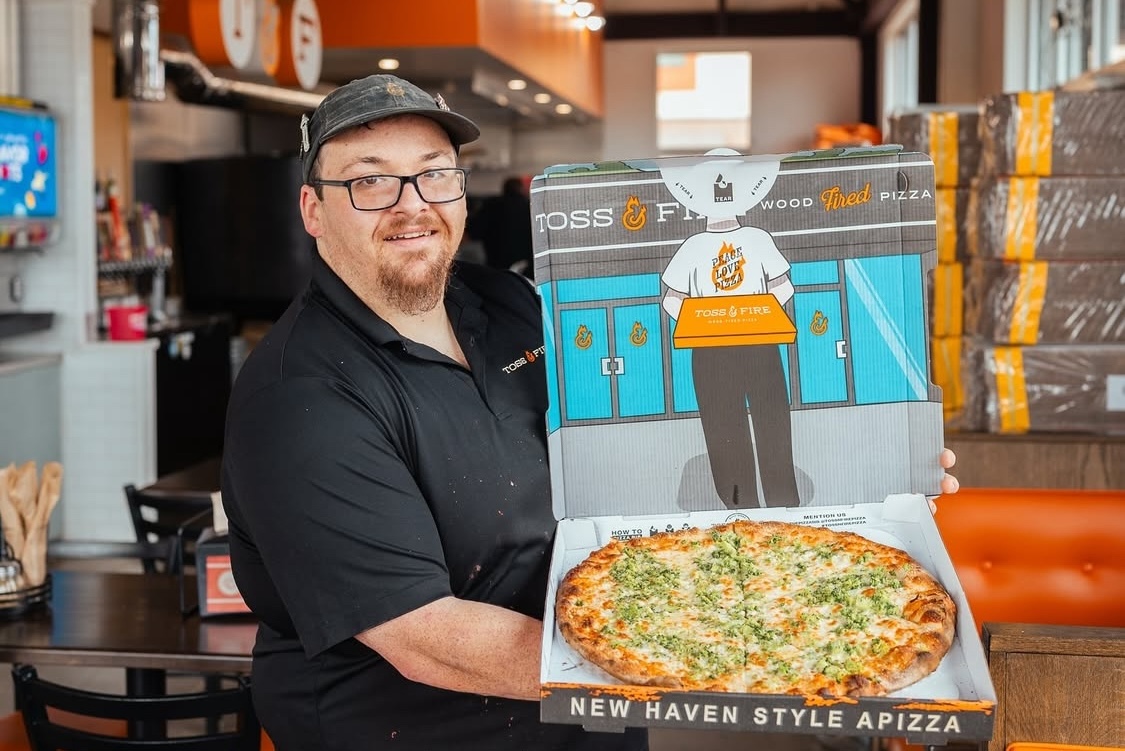 This photo shows Nick Sanford holding up a pizza in the Pizza Bib box.