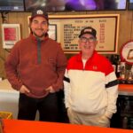 This photo shows Alex Koons and Paul Giannone standing side by side behind the counter at Paulie Gee's in New York.
