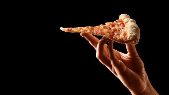 This photo shows a Hand holding slice of cheese pizza cut in slices