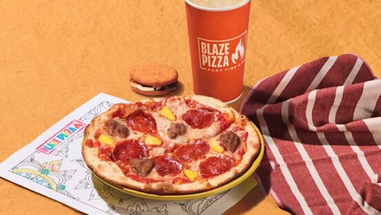 This photo shows a 7" kids pizza, a beverage cup with the Blaze Pizza logo, a cookie and a coloring sheet, with a red and white striped napkin.