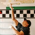 This photo shows a man spinning a round disc of dough high above his head.