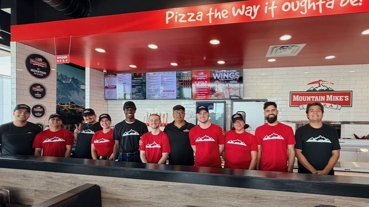 This photo shows a group of employees standing behind the ordering counter at a new location of Mountain Mike's Pizza.