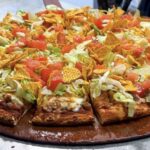 This photo shows the taco pizza from Happy Joe's, topped with ground beef, lettuce, tomatoes, cheese and corn chips.