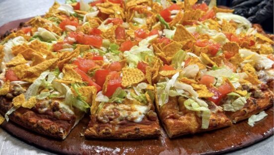 This photo shows the taco pizza from Happy Joe's, topped with ground beef, lettuce, tomatoes, cheese and corn chips.