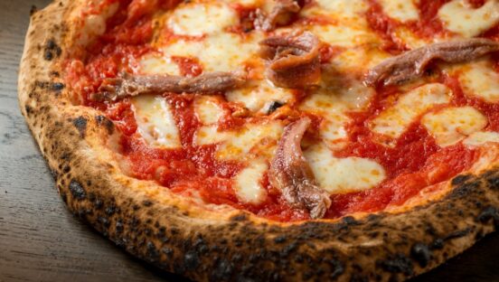 This photo shows a pizza with tomato, mozzarella and anchovies.