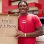 This photo shows a man in a red Casey's t-shirt holding an empty pizza box with words on the inside lid: "40% Off All Pizzas."