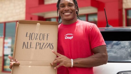 This photo shows a man in a red Casey's t-shirt holding an empty pizza box with words on the inside lid: "40% Off All Pizzas."