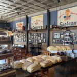 This photo shows the dining room of D'Arc's Pizza with trays of fresh-baked bread on a table in the forefront.