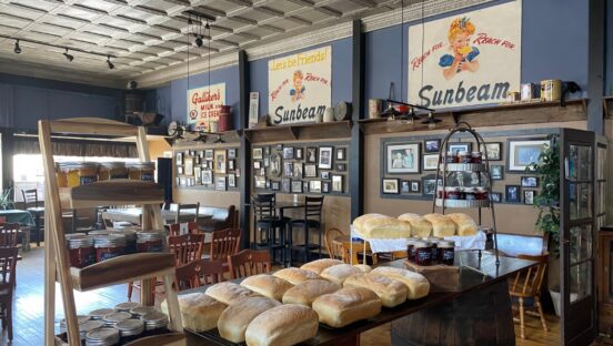 This photo shows the dining room of D'Arc's Pizza with trays of fresh-baked bread on a table in the forefront.