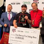 This photo shows Giovanni Labbate with Pizza Exp officials. He is holding a giant check for $1,000.