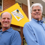 This photo shows Rick Rosenfield and Larry Flax (both wearing dressy blue shirts) standing outside in front of a California Pizza Kitchen sign.